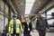 Manager supervisors and industrial worker in uniform walking in large metal factory hall and talking.