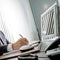 Manager at work. The expert hand of a businessman sitting at his desk, he holds the pen in front of his computer monitor that