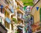 Manarola, Italy, September 12, 2018: colorful buildings houses with flags rows, balconies, shutter windows