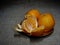 Mandarin or clementine oranges, dark still life on rustic hessian. Light painting technique. Three fruit, one part