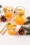 Mandarin cocktail with ice and mint in beautiful glasses and jug, fresh ripe citrus on white wooden background. Sweet orange juice