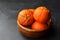 Mandarin organic fruits in wooden bowl on black background