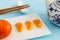 Mandarin, tangerine, or clementine with peeled segments or slices on rectangle plate with Chinese tea pot and chopsticks