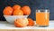 Mandarine and clementine juice served next to a bowl on a white wooden table.
