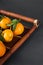 Mandarine fruite with leaves on a bamboo tray on a grey background