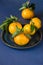 Mandarine fruite with leaves on ceramic plate on blue background