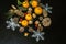 Mandarins with leaves, sprig of cypress,different conifer cones with snowflakes on a black plywood