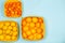 Mandarins, lemons and oranges in yellow baskets over a light blue background with copy space