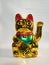 Maneki Neko,  an oriental Japanese lucky cat, a golden figurine with its left hand raised.