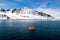 Maneuvering orange lifeboat in water in Arctic waters, Svalbard. Abandon ship drill. Lifeboat training. Man over board drill