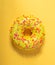 Mango donut with icing on yellow background