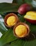 Mango ice cream sorbet in coconut peel with half fresh mango on palm leaves