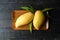 Mango and leaf in wood tray on wood table