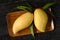 Mango and leaves in wood tray on wood table