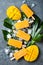 Mango popsicles over green tropical palm leaf on grey stone background.
