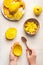 Mango preparation step by step. Female hands holding empty mango peel and spoon on white background with mango cubes in coconut