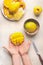 Mango preparation step by step. Female hands holding half diced mango on white background with coconut bowl and fruits plate, top