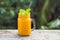 Mango smoothie in a glass Mason jar and mango on a green background. Mango shake. Tropical fruit concept