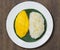 The mango sticky rice with peeled split mung bean on white plate