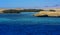 A mango tree among coral reefs in the form of mountains and rocks against the blue sky and clear sea water.