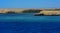 A mango tree among coral reefs in the form of mountains and rocks against the blue sky and clear sea water.