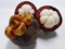 Mangosteen. A tropical fruit with sweet juicy white segments of flesh inside a thick reddish-brown rind.