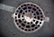 Manhole with metal cover in asphalt with white road marking line