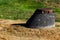 Manhole raised on a concrete rise next to brown and green grass