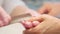 Manicure care procedure. Closeup view of beautician\'s hand filing nails of woman in salon.