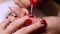 Manicure Caucasian hand of manicurist draws snowflake on client\'s red nail