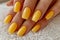 Manicure closeup. Woman yellow nails close-up. Nail care in beauty salon. Spa healthy treatments for female hands. Fashion bright