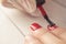Manicure master paints the nails of the client. Manicurist with a brush paint your nails in red.