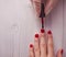 Manicure master paints the nails of the client. Manicurist with a brush paint your nails in red.