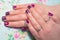 Manicure with rhinestones: a woman shows hands with a manicure made with colored lacquer and rhinestones, jeweled rings on the