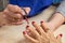 Manicure specialist applying varnish to nails.