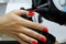 Manicure specialist in black gloves cares about hands nails. Manicurist paints nails with red nail polish