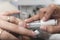 A manicurist applies white gel polish to the ring finger of a female customer