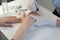 Manicurist is applying cuticle remover on nails on client`s hand, closeup view.