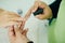 Manicurist applying cuticle softener or clear nail varnish to the fingernails of a lady client in a spa or beauty salon