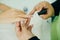 Manicurist applying cuticle softener or clear nail varnish to the fingernails of a lady client in a spa or beauty salon