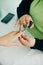 Manicurist applying cuticle softener or clear nail varnish to the fingernails of a lady client in a spa or beauty salon