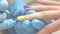Manicurist applying transparent gel on polished nail.