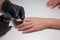 Manicurist black gloves doing a manicure at the beauty salon on a white background. Nail Polish colors Nude. Beautiful