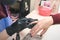 The manicurist in black latex gloves covers the client`s nails with a colored gel polish