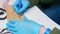 Manicurist in blue gloves wirtes on paper bag for sterilised manicure instruments