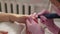 Manicurist cuts nails with a machine to a client in a manicure salon.