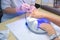 Manicurist master painting client`s nails gel shellac, another hand in UV lamp.