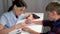 Manicurist master woman is polishing her son`s boy nails using file at home.