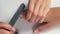 Manicurist master woman is polishing son`s boy nails using file, hands closeup.