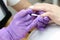 A manicurist paints his nails with white varnish